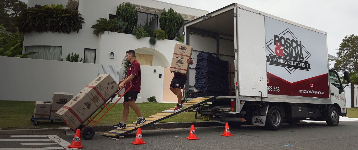 Posch & Silva crew wheeling boxes up the ramp of a branded truck outside a customer&rsquo;s home